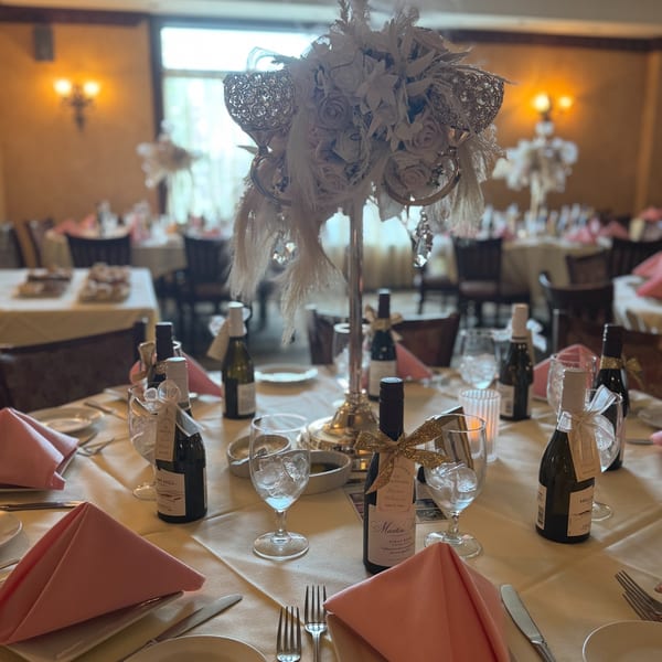 Elegantly set tables with pink napkins, mini wine bottles, and floral centerpieces at Luciano's Ristorante.