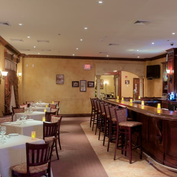 The interior of Luciano's Ristorante & Lounge, featuring dining tables and a long wooden bar.