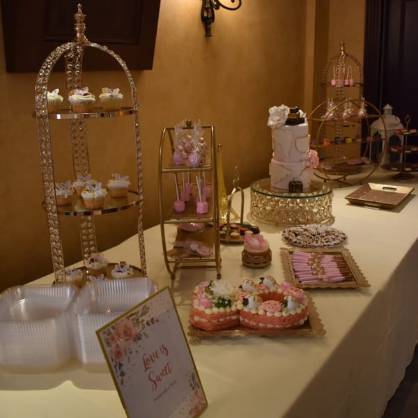 A dessert table with cupcakes, cake pops, a tiered cake, and other sweets.