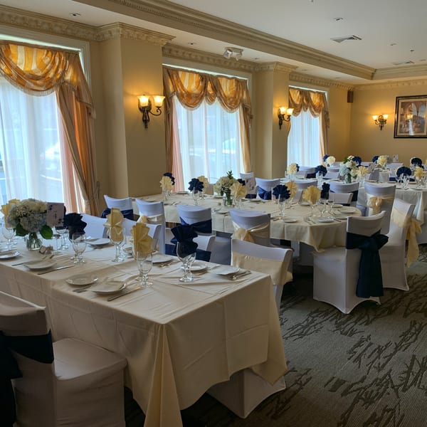 Elegant dining room at Luciano's Ristorante with tables set for a banquet, featuring blue and gold decor.