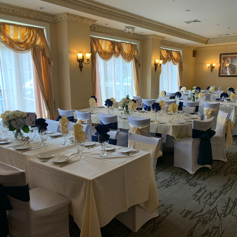 Elegant dining room at Luciano's Ristorante with tables set for a banquet, featuring blue and gold decor.