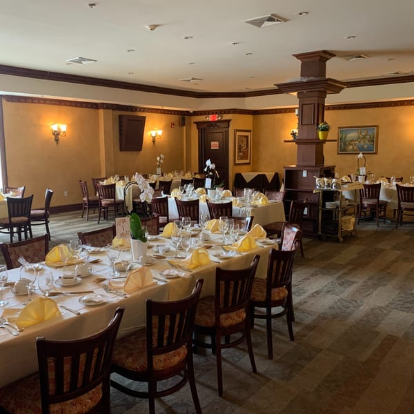 Elegant dining room at Luciano's Ristorante & Lounge with set tables, yellow napkins, and warm lighting.