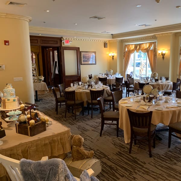 A Luciano's Ristorante dining room with round tables set for guests and a dessert display.