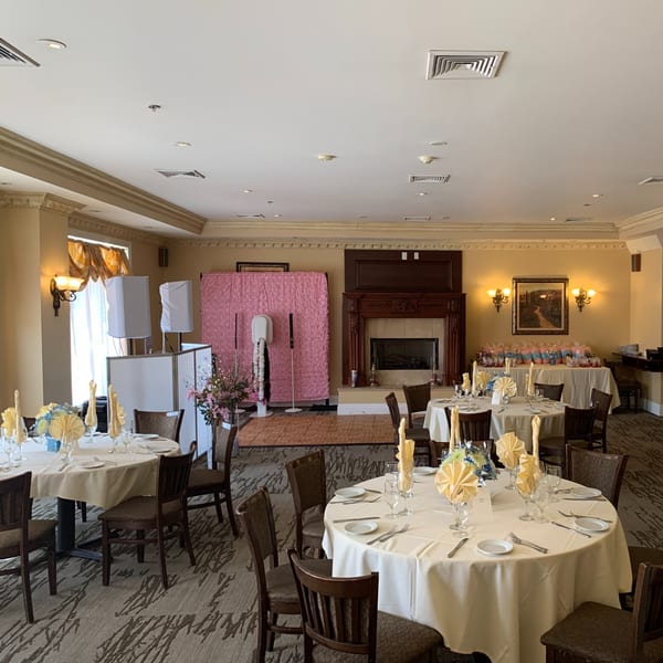 Elegant dining room at Luciano's Ristorante with set tables, a fireplace, and a pink photo booth.