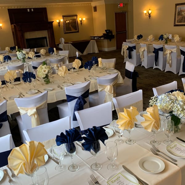 Elegant dining room at Luciano's Ristorante with tables set with white linens, blue and gold accents.