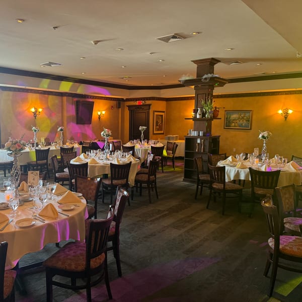 Elegant Italian restaurant dining room with set tables, floral centerpieces, and warm lighting.