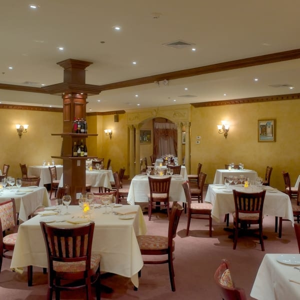 An empty dining room at Luciano's Ristorante & Lounge with tables set for dinner.