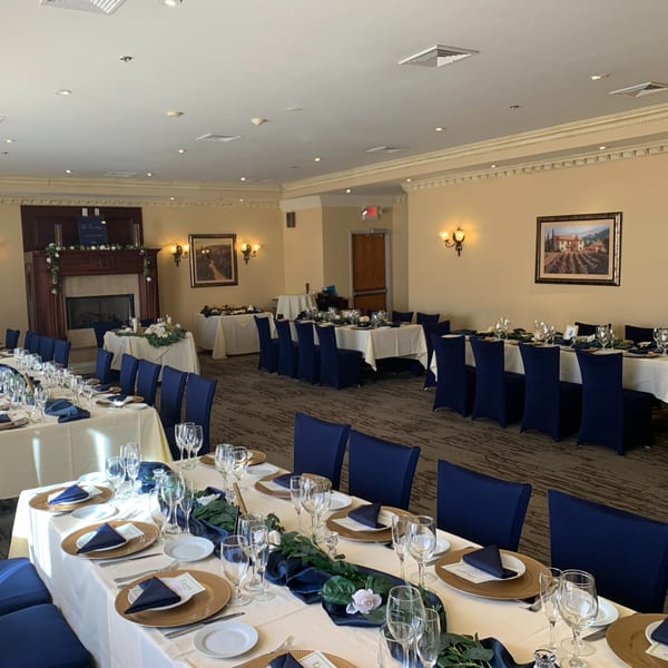 Elegant dining room at Luciano's Ristorante with set tables, blue chairs, and a fireplace.