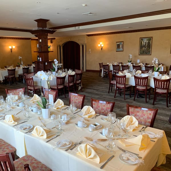 Elegant dining room at Luciano's Ristorante & Lounge with set tables, yellow tablecloths, and ornate decor.