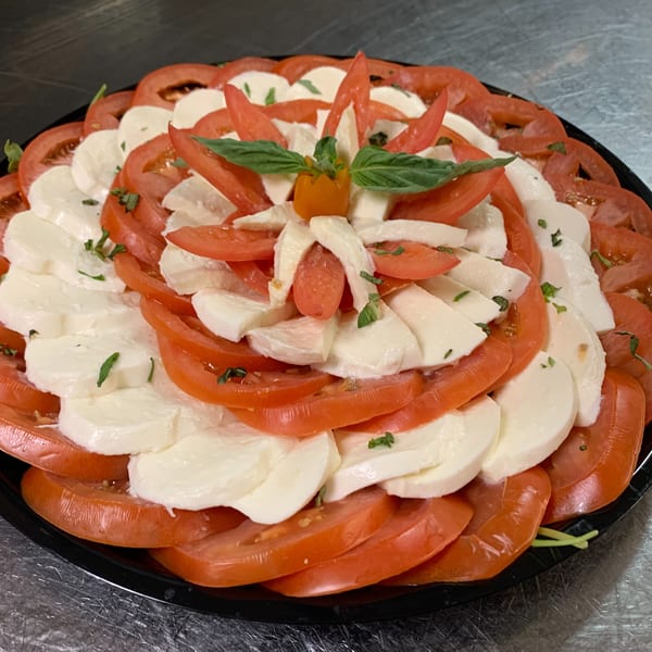 A vibrant Caprese salad with sliced tomatoes, mozzarella, basil, and a small orange tomato.