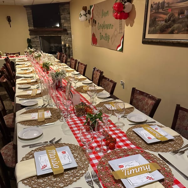 Long dining table set for a private event at Luciano's Ristorante, decorated with red and white checkered runners.
