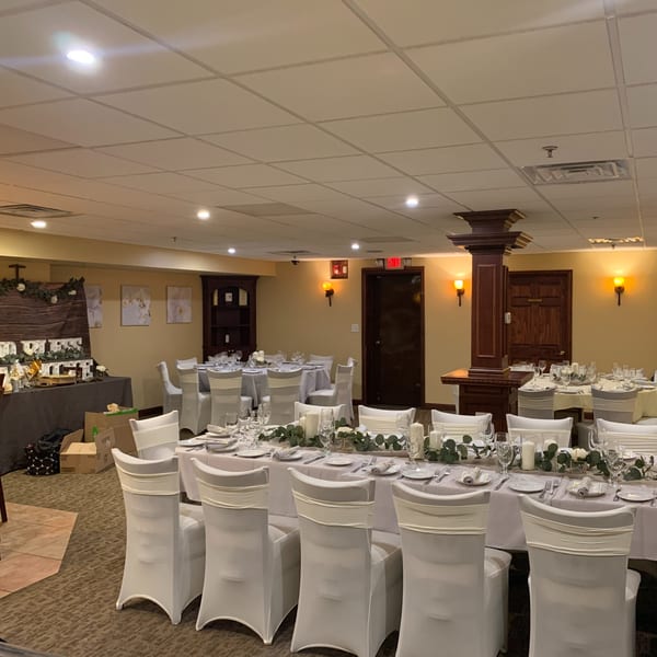 Elegant dining room at Luciano's Ristorante & Lounge set with white tablecloths, chairs, and floral centerpieces.