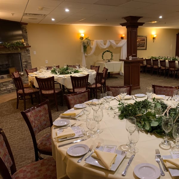 Luciano's Ristorante & Lounge dining room set for an event with round tables, place settings, and greenery.