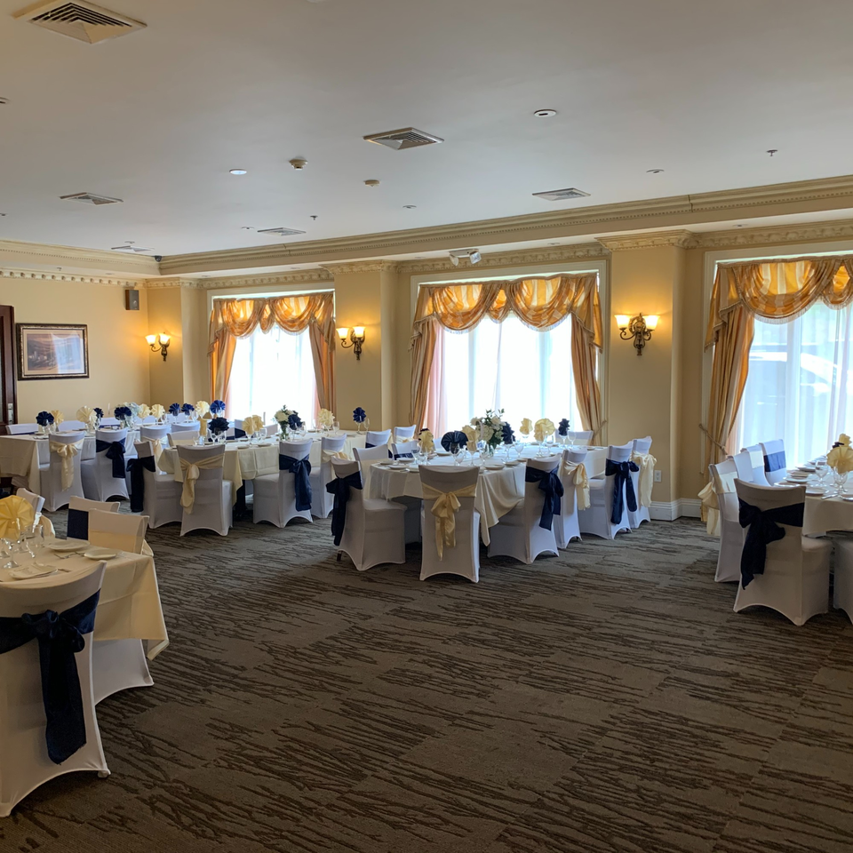 Elegant dining room at Luciano's Ristorante with round tables, white chairs, and blue and gold accents.