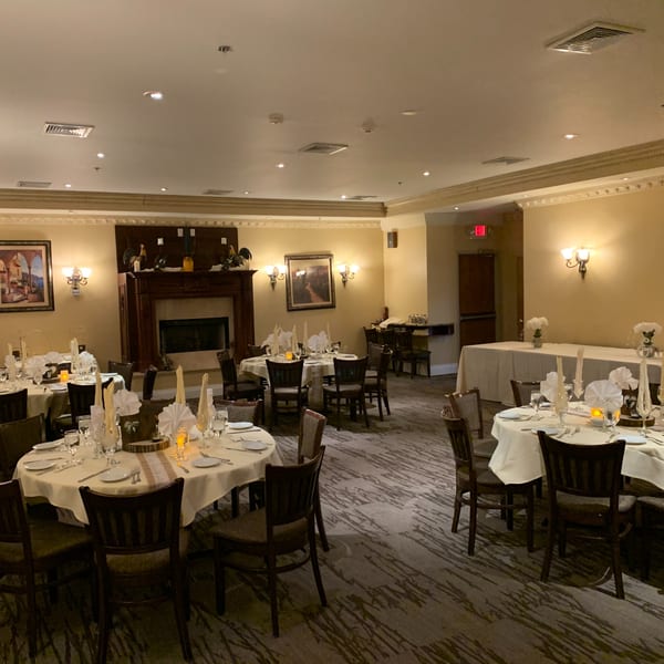 Elegant dining room at Luciano's Ristorante with set tables, a fireplace, and warm lighting.