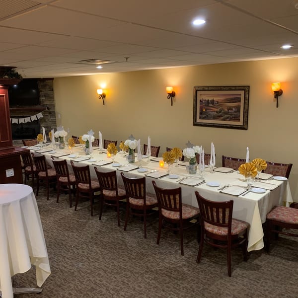 Long dining table set for a private event at Luciano's Ristorante, with elegant place settings and decor.