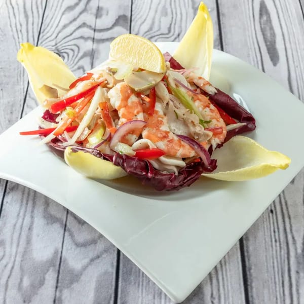 Luciano's Ristorante & Lounge's seafood salad with shrimp, squid, red onions, and peppers, garnished with a lemon wedge.