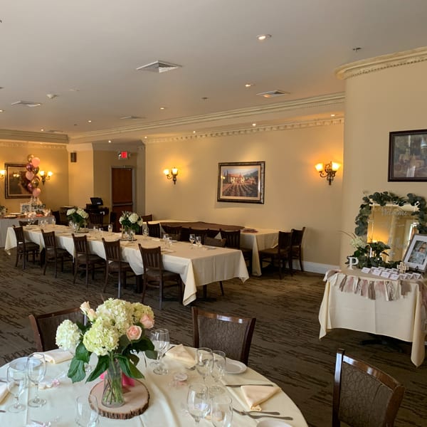 Elegant dining room at Luciano's Ristorante & Lounge set with white tablecloths, floral centerpieces, and warm lighting.