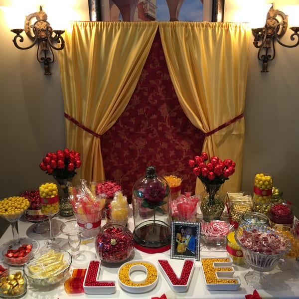 A dessert table with red and yellow candies, a framed photo, and a "LOVE" sign.