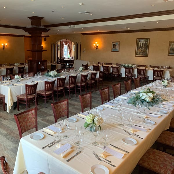 Elegant dining room at Luciano's Ristorante & Lounge with long tables set for a banquet.