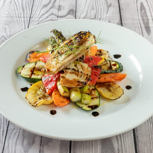 Grilled vegetables, including zucchini, carrots, bell peppers, and fennel, drizzled with balsamic glaze.