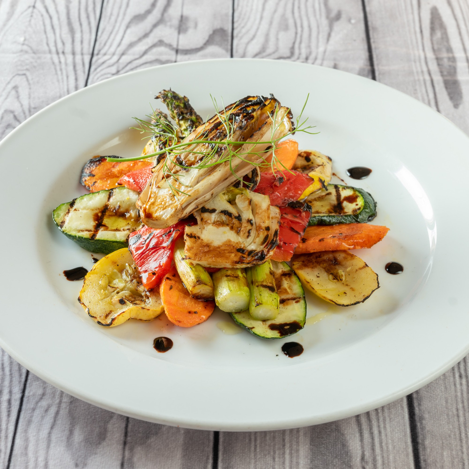 Grilled vegetables, including zucchini, carrots, bell peppers, and fennel, drizzled with balsamic glaze.