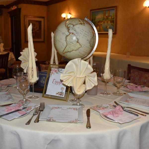 A dining table set with a globe centerpiece, wine glasses, and menus at Luciano's Ristorante & Lounge.