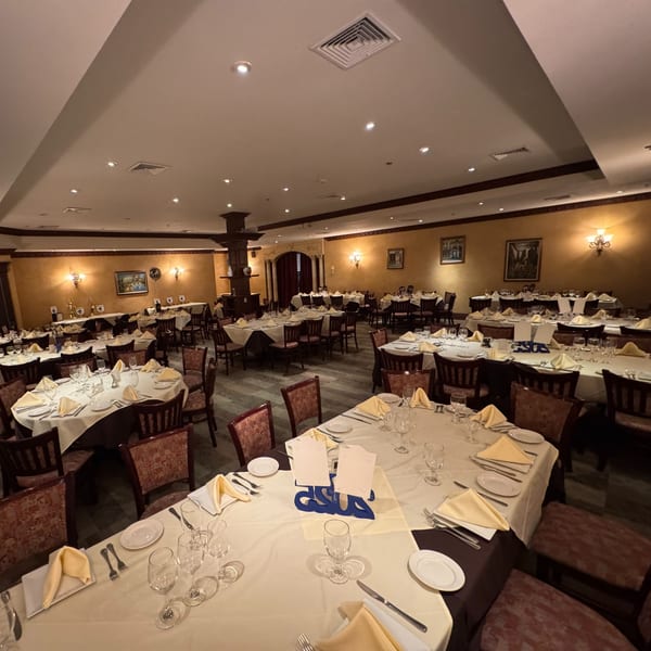 A large, elegant dining room at Luciano's Ristorante & Lounge with many set tables and warm lighting.