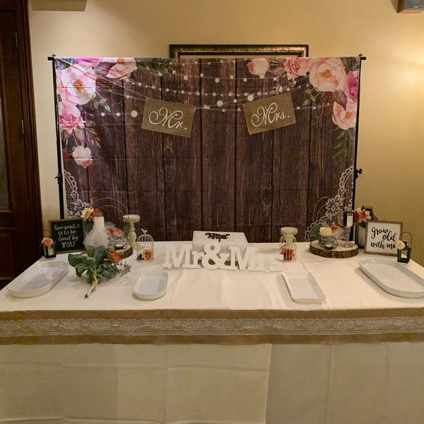 A decorated table with a "Mr. & Mrs." sign, floral backdrop, and wedding-themed decor.