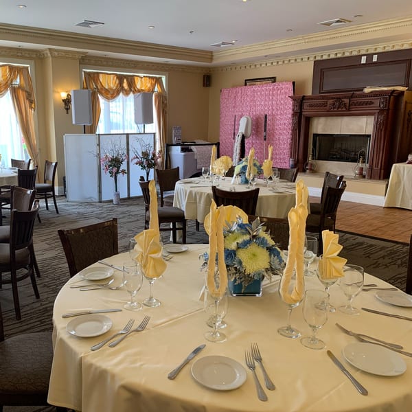 Elegant dining room at Luciano's Ristorante with set tables, floral centerpieces, and a DJ booth.
