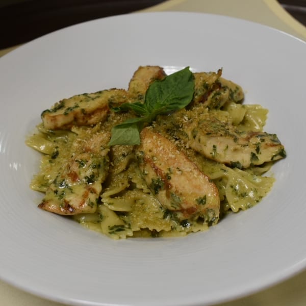 Luciano's Ristorante & Lounge's chicken pesto farfalle pasta, garnished with fresh basil and breadcrumbs.