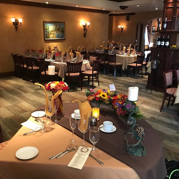 Elegant dining room at Luciano's Ristorante with set tables, floral centerpieces, and warm lighting.
