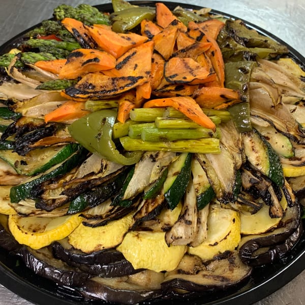 A large platter of grilled vegetables, including carrots, zucchini, bell peppers, and eggplant.