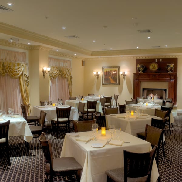 Elegant dining room at Luciano's Ristorante with set tables, a fireplace, and warm lighting.