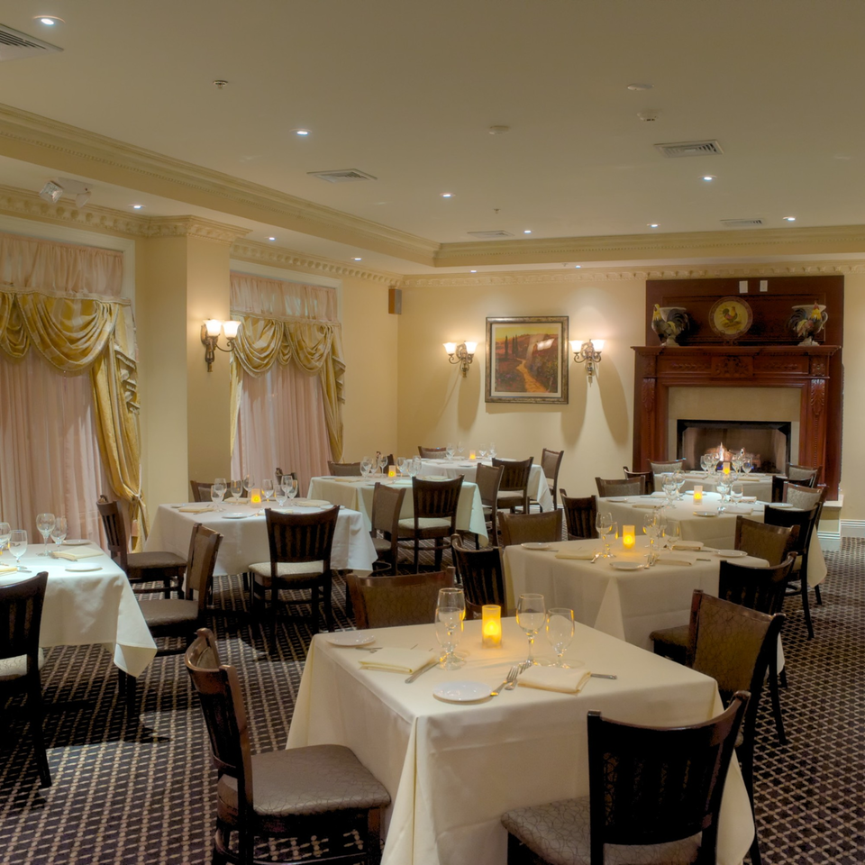 Elegant dining room at Luciano's Ristorante with set tables, a fireplace, and warm lighting.
