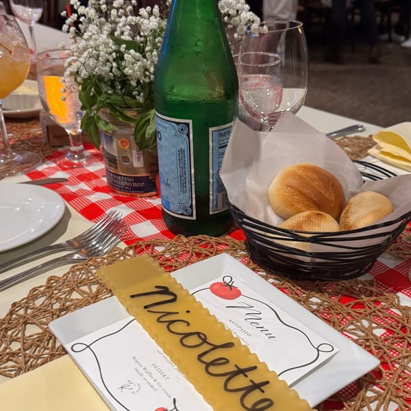 A Luciano's Ristorante table set with bread, drinks, a floral centerpiece, and a menu.