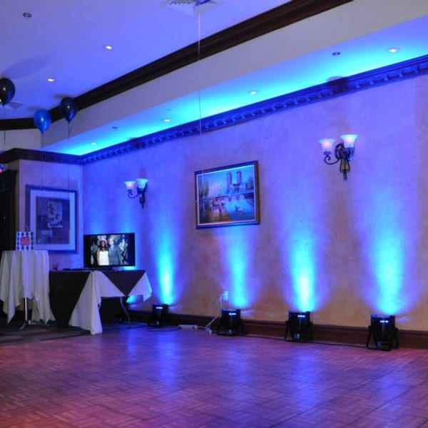 Luciano's Ristorante & Lounge event space with blue uplighting, balloons, and a TV display.