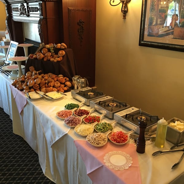 A buffet table with various toppings, portable burners, and a large bread display at Luciano's Ristorante.