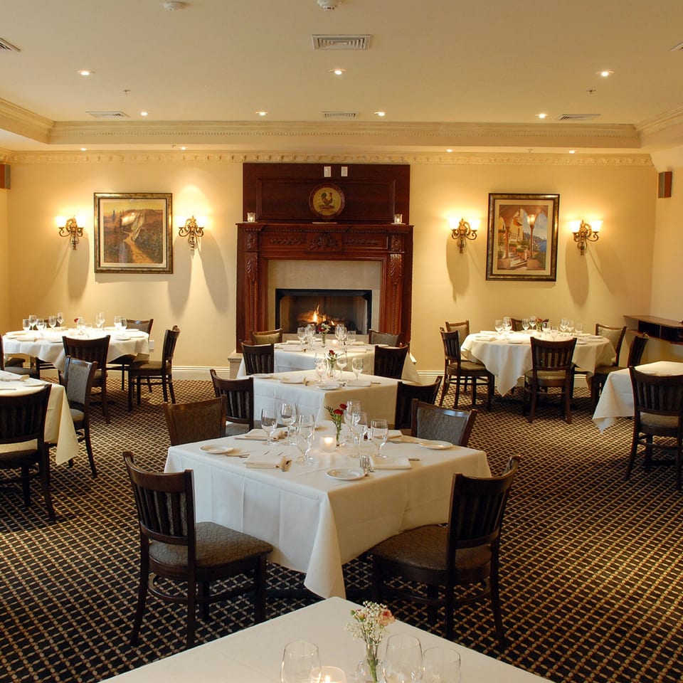 Elegant dining room at Luciano's Ristorante with set tables, a lit fireplace, and warm lighting.