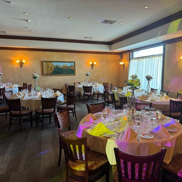 Elegant dining room at Luciano's Ristorante with set tables, floral centerpieces, and warm lighting.
