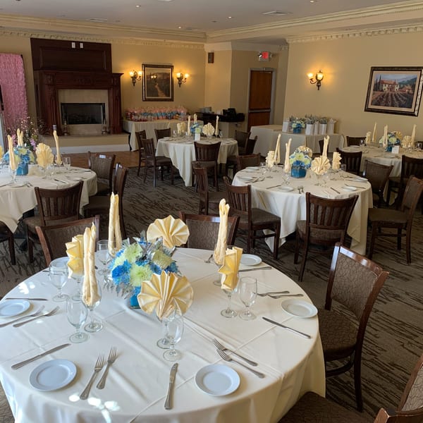 Elegant dining room at Luciano's Ristorante with round tables set with white tablecloths and floral centerpieces.
