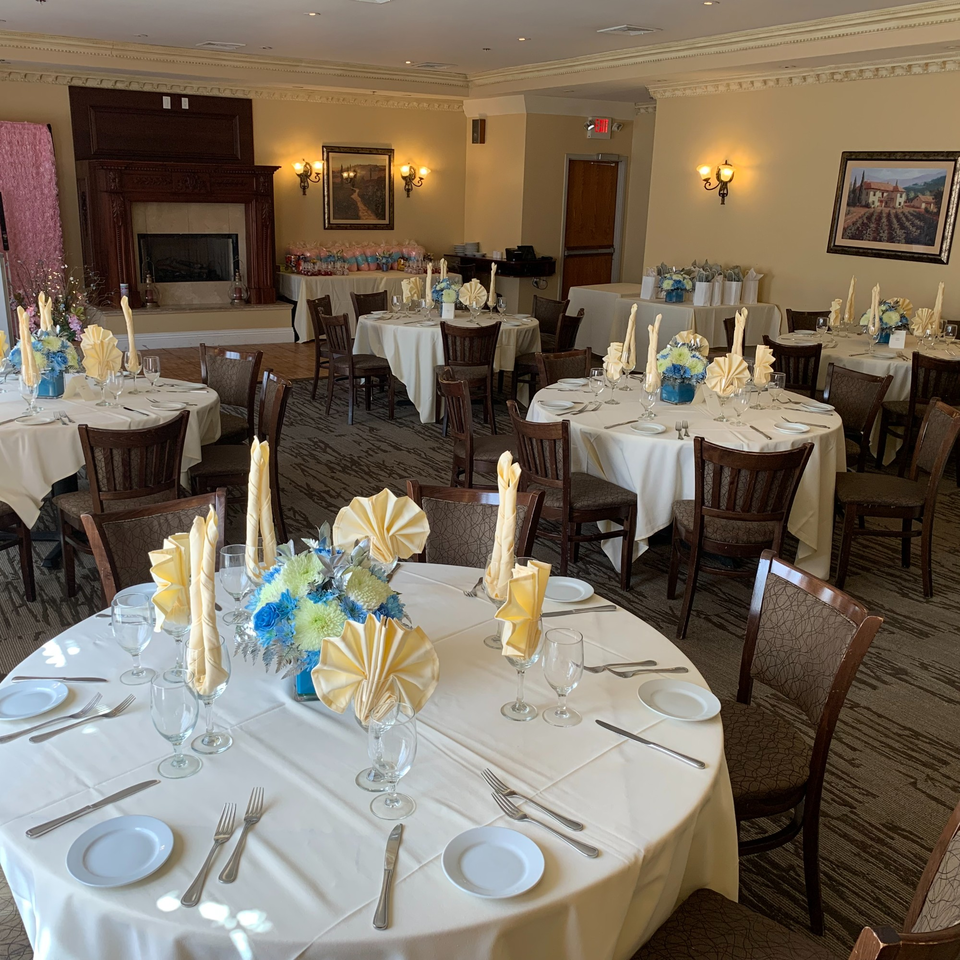Elegant dining room at Luciano's Ristorante with round tables set with white tablecloths and floral centerpieces.