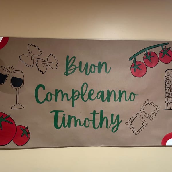 A "Buon Compleanno Timothy" sign with Italian-themed drawings like pasta, wine, tomatoes, and the Leaning Tower of Pisa.