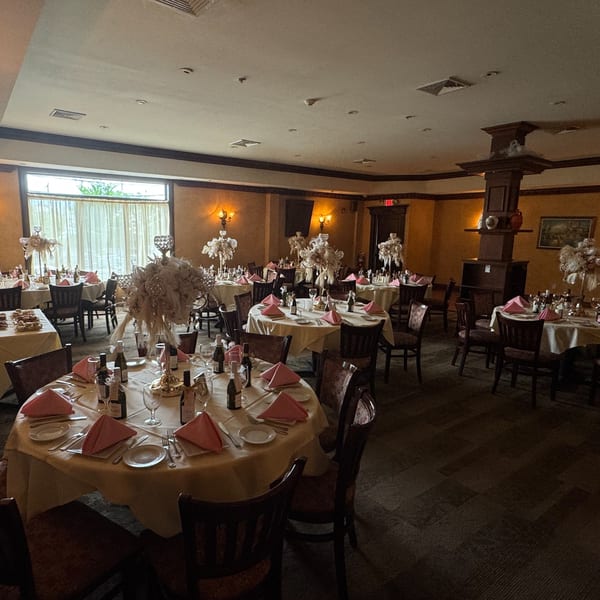 Elegant dining room at Luciano's Ristorante with round tables, pink napkins, and elaborate centerpieces.